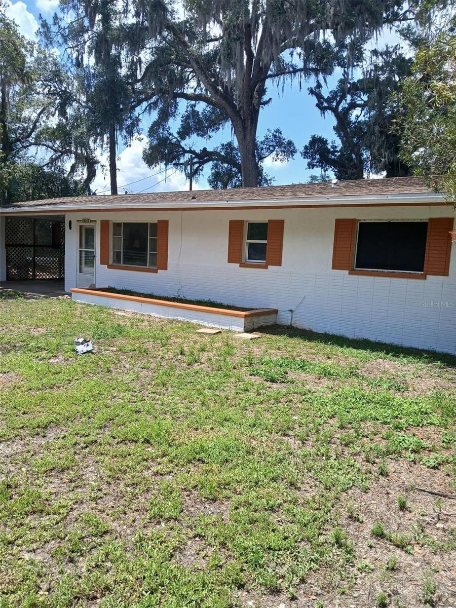 34745 Gardenia Way, Dade City, FL 33523 - rear view of property with a lawn and a carport