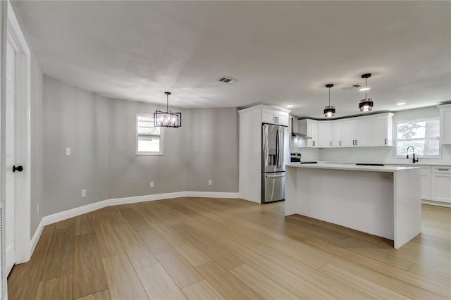 10744 Drummond Rd, Tampa, FL 33615 - kitchen featuring appliances with stainless steel finishes, a sink, wall chimney range hood, a chandelier, and light countertops