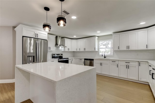 10744 Drummond Rd, Tampa, FL 33615 - kitchen featuring appliances with stainless steel finishes, wall chimney range hood, a sink, light wood finished floors, and white cabinets
