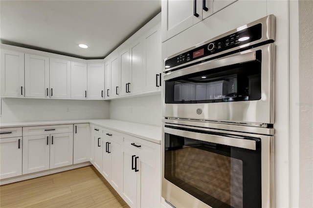 10744 Drummond Rd, Tampa, FL 33615 - kitchen featuring double oven, white cabinets, light wood-style flooring, light countertops, and recessed lighting