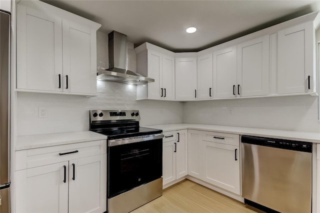 10744 Drummond Rd, Tampa, FL 33615 - kitchen featuring appliances with stainless steel finishes, wall chimney range hood, light wood-type flooring, light countertops, and white cabinets