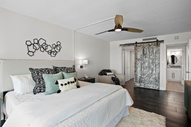 17920 Gulf Blvd Unit 1806, Redington Shores, FL 33708 - bedroom with wood tiled floors, a barn door, ceiling fan, a textured ceiling, and connected bathroom
