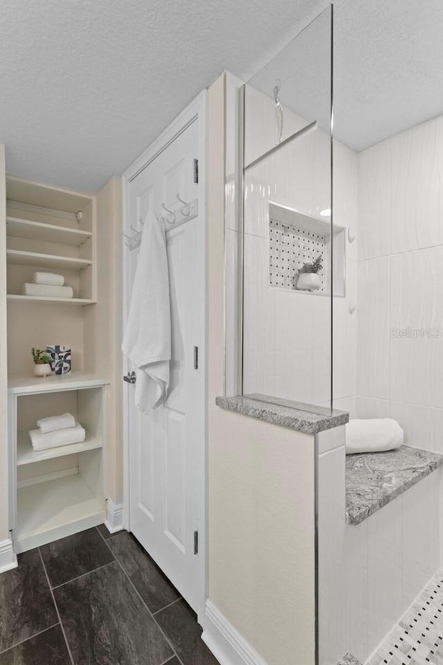 17920 Gulf Blvd Unit 1806, Redington Shores, FL 33708 - bathroom featuring a textured ceiling, walk in shower, and baseboards