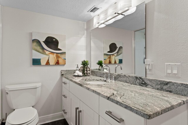 17920 Gulf Blvd Unit 1806, Redington Shores, FL 33708 - bathroom featuring vanity, a textured ceiling, toilet, wood finished floors, and baseboards