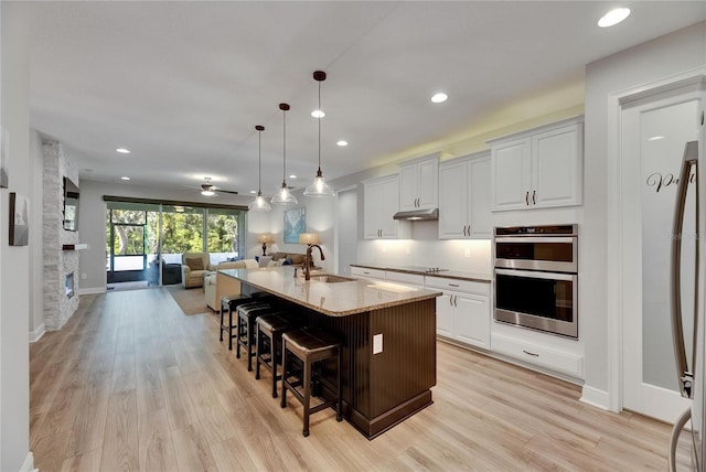 12957 Satin Lily Dr, Riverview, FL 33579 - kitchen with a sink, stainless steel double oven, open floor plan, a kitchen bar, and recessed lighting