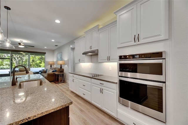12957 Satin Lily Dr, Riverview, FL 33579 - kitchen featuring a sink, stainless steel double oven, under cabinet range hood, light wood-style flooring, and light stone countertops