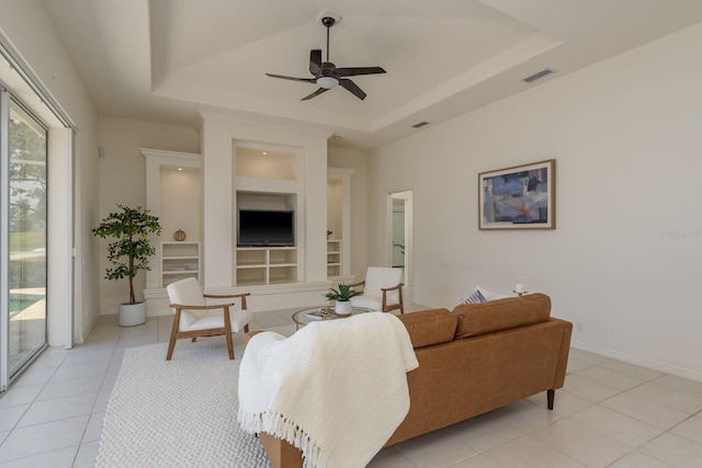 987 Chickadee Dr, Venice, FL 34285 - living room featuring a tray ceiling, light tile patterned flooring, built in features, a ceiling fan, and baseboards