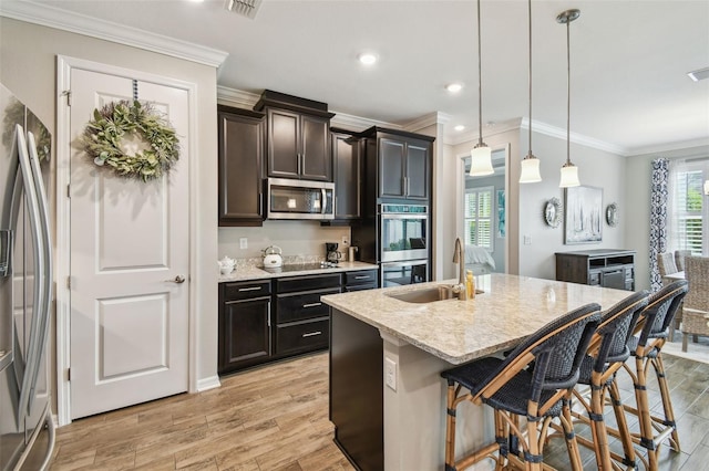 751 Cajeput Loop, Tarpon Springs, FL 34689 - kitchen with stainless steel appliances, light wood-style flooring, a kitchen bar, a sink, and an island with sink