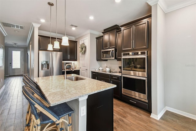 751 Cajeput Loop, Tarpon Springs, FL 34689 - kitchen featuring stainless steel appliances, a sink, ornamental molding, light wood finished floors, and dark brown cabinetry