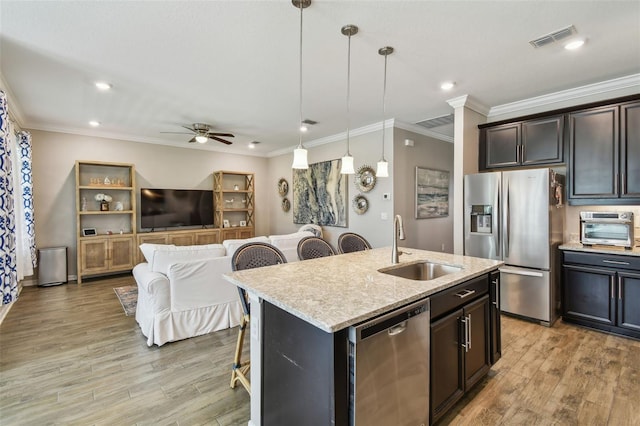 751 Cajeput Loop, Tarpon Springs, FL 34689 - kitchen with appliances with stainless steel finishes, a sink, a breakfast bar, light wood-style flooring, and ornamental molding