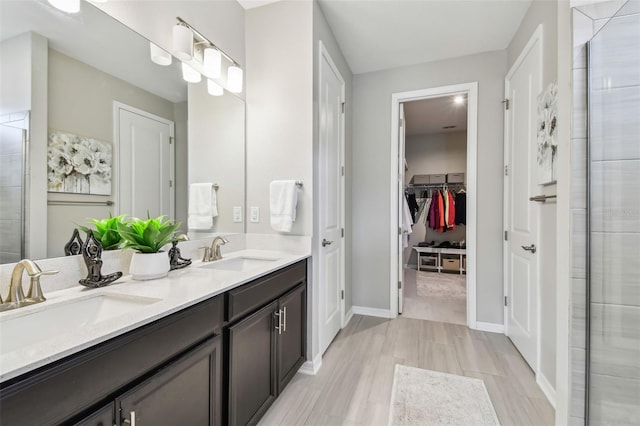 751 Cajeput Loop, Tarpon Springs, FL 34689 - bathroom with double vanity, a spacious closet, baseboards, and a tile shower