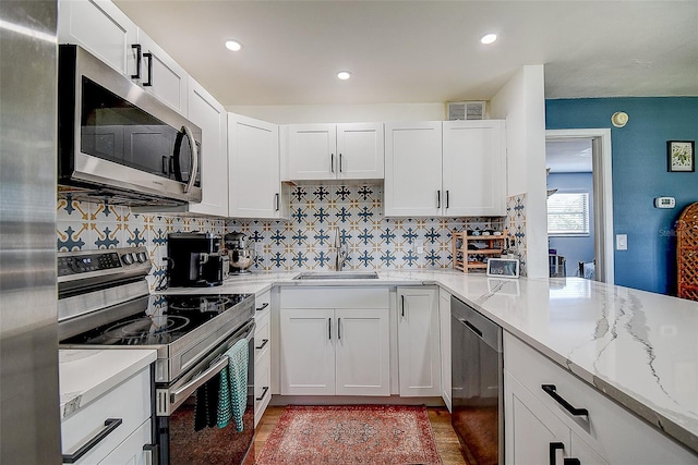 4050 4th St N Unit 205, Saint Petersburg, FL 33703 - kitchen with appliances with stainless steel finishes, a sink, backsplash, light stone countertops, and white cabinetry