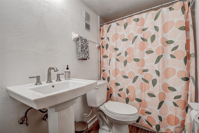 4050 4th St N Unit 205, Saint Petersburg, FL 33703 - bathroom featuring toilet, a textured wall, wood finished floors, and curtained shower