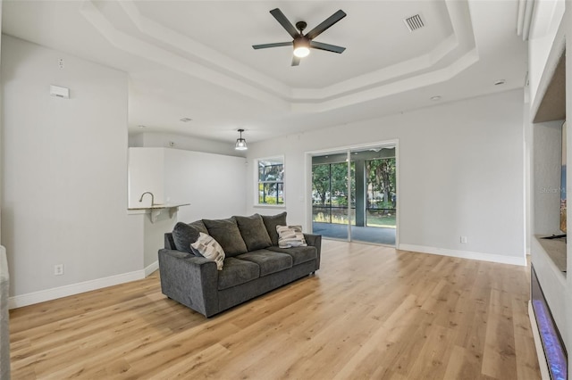707 9th Ave SW, Ruskin, FL 33570 - living area featuring a raised ceiling, ceiling fan, light wood-style floors, and baseboards
