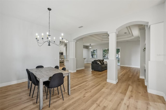 707 9th Ave SW, Ruskin, FL 33570 - dining space with decorative columns, arched walkways, a tray ceiling, light wood-style floors, and baseboards