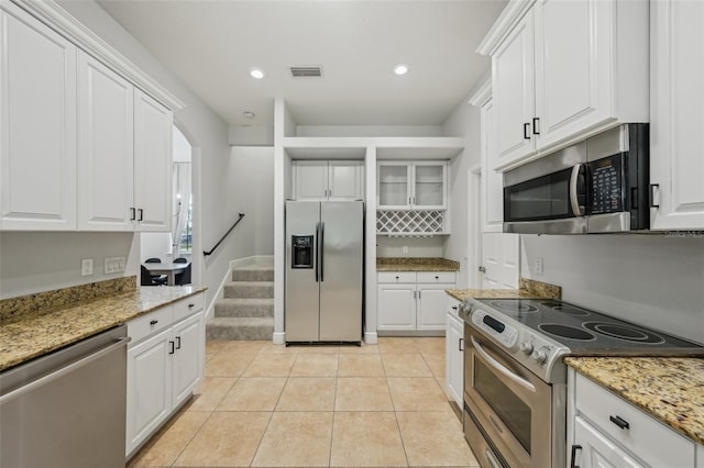 707 9th Ave SW, Ruskin, FL 33570 - kitchen featuring appliances with stainless steel finishes, white cabinetry, light tile patterned floors, light stone counters, and recessed lighting