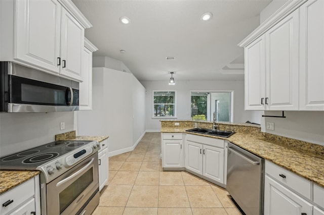 707 9th Ave SW, Ruskin, FL 33570 - kitchen with appliances with stainless steel finishes, a sink, white cabinetry, light tile patterned floors, and a peninsula