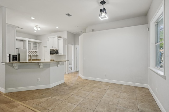 707 9th Ave SW, Ruskin, FL 33570 - kitchen with appliances with stainless steel finishes, a breakfast bar, light stone countertops, white cabinetry, and recessed lighting