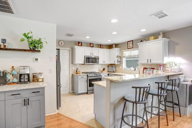 5525 Turtle Crossing Loop, Tampa, FL 33625 - kitchen featuring stainless steel appliances, a peninsula, decorative backsplash, a breakfast bar area, and white cabinets