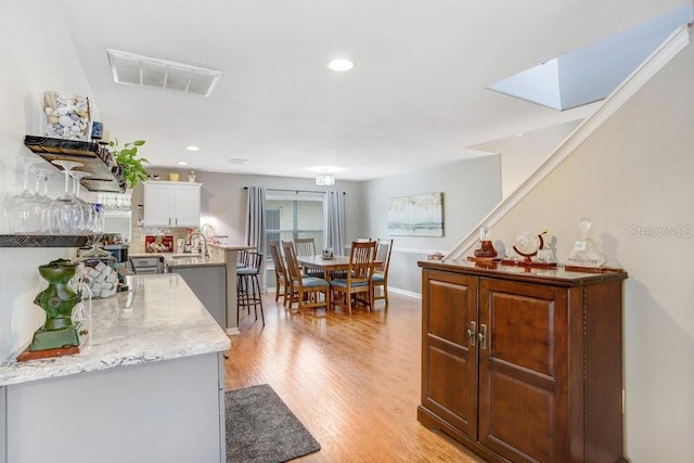 5525 Turtle Crossing Loop, Tampa, FL 33625 - kitchen with light wood-style floors, white cabinets, a sink, recessed lighting, and a skylight