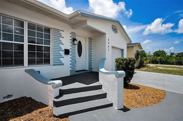 5642 9th Ave N, Saint Petersburg, FL 33710 - view of exterior entry featuring an attached garage and stucco siding