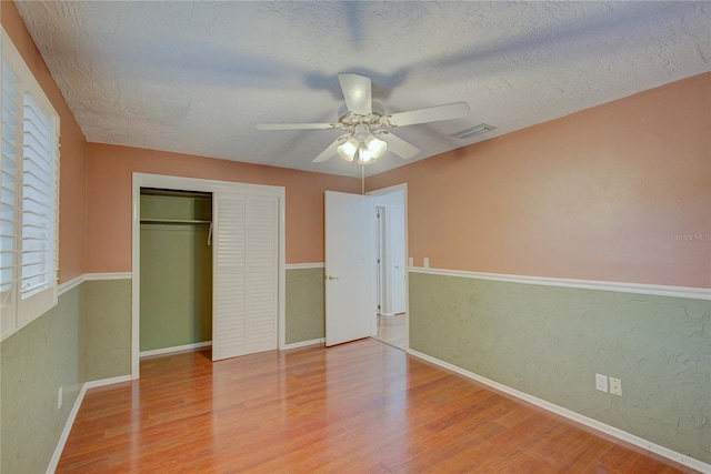 31 Freshwater Dr, Palm Harbor, FL 34684 - unfurnished bedroom with wood finished floors, a closet, a textured ceiling, a ceiling fan, and baseboards
