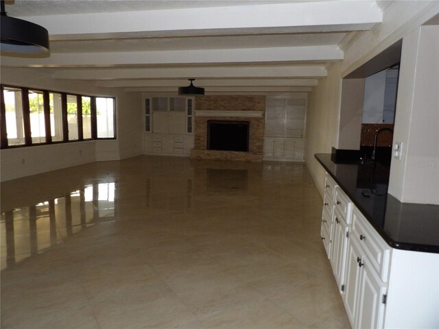 31 Freshwater Dr, Palm Harbor, FL 34684 - kitchen with beamed ceiling, dark countertops, white cabinetry, a fireplace, and open floor plan