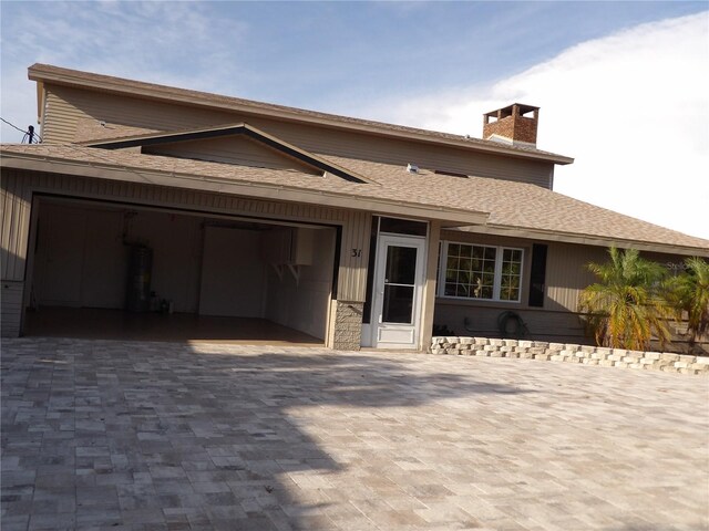 31 Freshwater Dr, Palm Harbor, FL 34684 - view of front of home featuring an attached garage, decorative driveway, a chimney, water heater, and a shingled roof