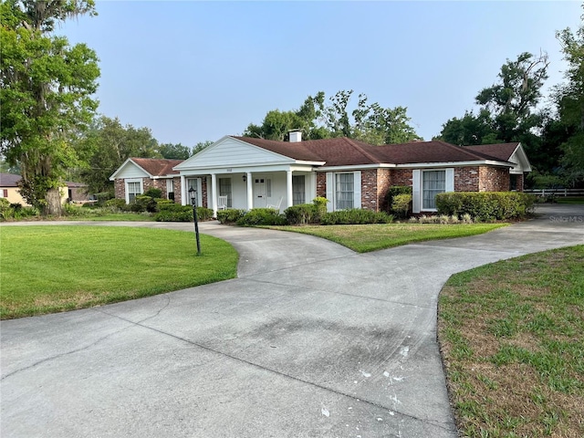 1002 W Pinedale Dr, Plant City, FL 33563 - view of front of house with curved driveway, a front lawn, brick siding, and a chimney