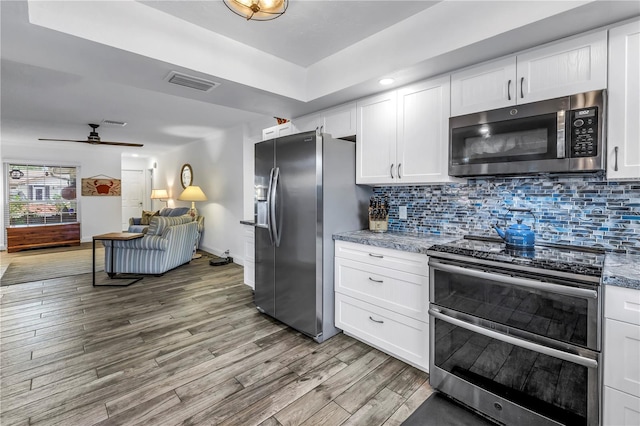 9611 107th Ave N, Largo, FL 33773 - kitchen with appliances with stainless steel finishes, wood finished floors, white cabinetry, decorative backsplash, and ceiling fan