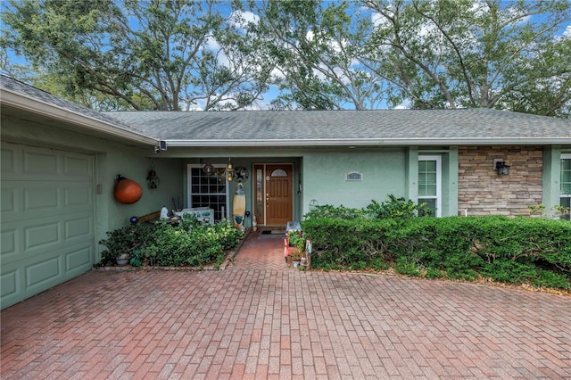 9611 107th Ave N, Largo, FL 33773 - entrance to property featuring a garage, stucco siding, roof with shingles, and decorative driveway