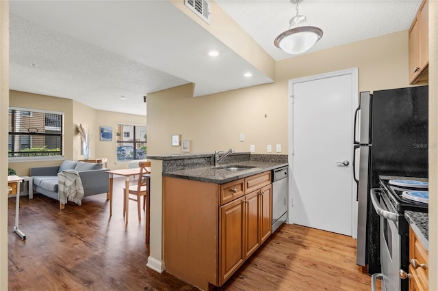 11901 4th St N Unit 5111, Saint Petersburg, FL 33716 - kitchen featuring appliances with stainless steel finishes, a sink, open floor plan, light wood-style flooring, and dark stone countertops