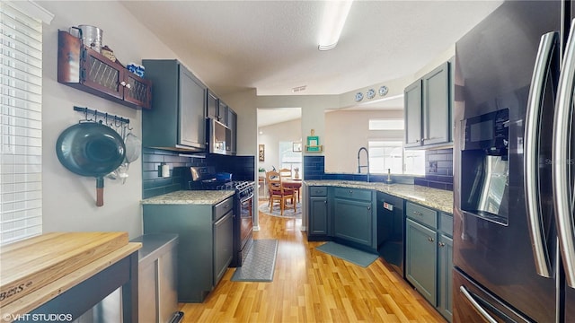 19635 Bellehurst Loop, Land O Lakes, FL 34638 - kitchen featuring stainless steel appliances, light wood-type flooring, tasteful backsplash, light stone counters, and a sink
