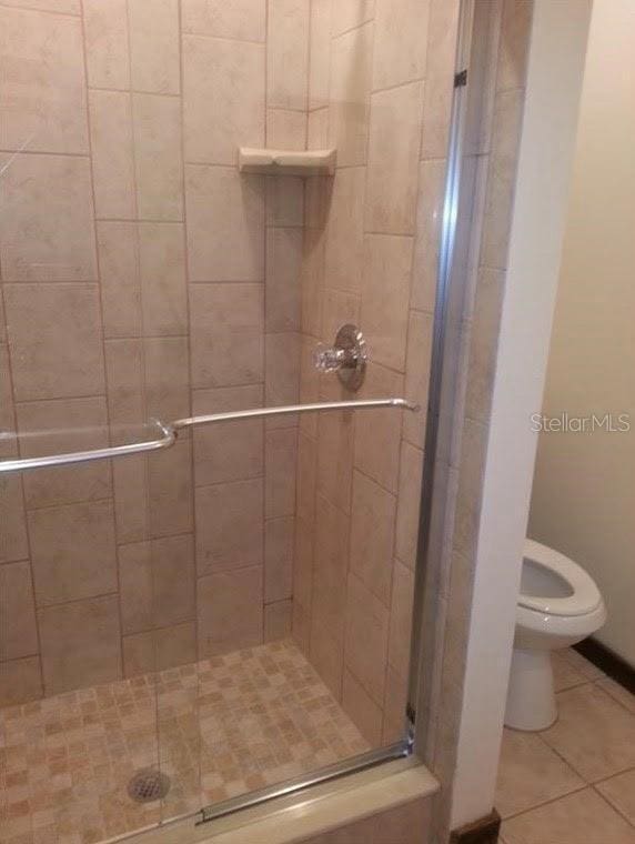 5310 Pebble Beach Dr Unit F, Orlando, FL 32811 - bathroom featuring a shower stall, toilet, and tile patterned floors