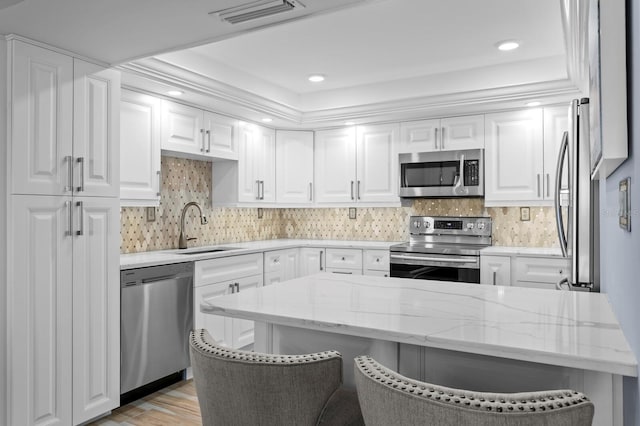 17920 Gulf Blvd Unit 1901, Redington Shores, FL 33708 - kitchen with appliances with stainless steel finishes, a sink, white cabinetry, a kitchen bar, and recessed lighting