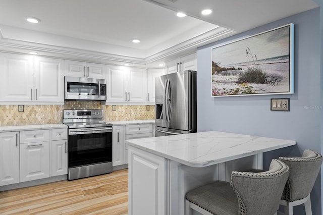 17920 Gulf Blvd Unit 1901, Redington Shores, FL 33708 - kitchen with stainless steel appliances, light wood-style floors, white cabinets, a breakfast bar, and light stone counters