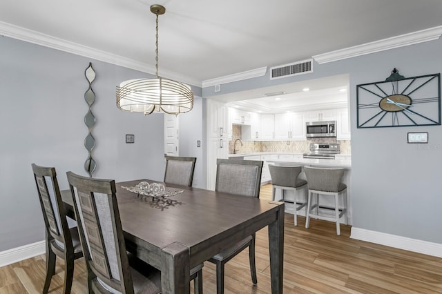 17920 Gulf Blvd Unit 1901, Redington Shores, FL 33708 - dining room featuring crown molding, a chandelier, light wood finished floors, and baseboards