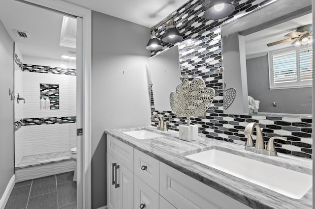 17920 Gulf Blvd Unit 1901, Redington Shores, FL 33708 - bathroom featuring double vanity, toilet, a tile shower, tasteful backsplash, and ceiling fan