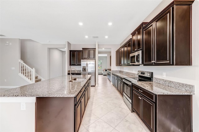11726 Sunburst Marble Rd, Riverview, FL 33579 - kitchen featuring stainless steel appliances, a sink, a kitchen island with sink, dark brown cabinetry, and light tile patterned floors
