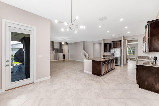 11726 Sunburst Marble Rd, Riverview, FL 33579 - kitchen with stainless steel fridge with ice dispenser, a chandelier, a center island with sink, dark brown cabinets, and light stone counters