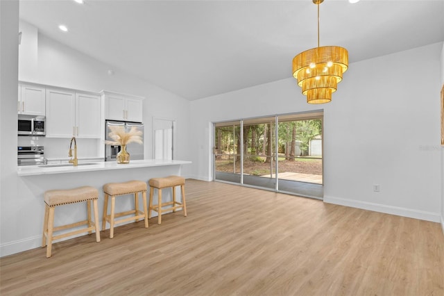 7644 Conrad St, Wesley Chapel, FL 33544 - kitchen with stainless steel appliances, light wood-type flooring, a breakfast bar area, high vaulted ceiling, and a sink
