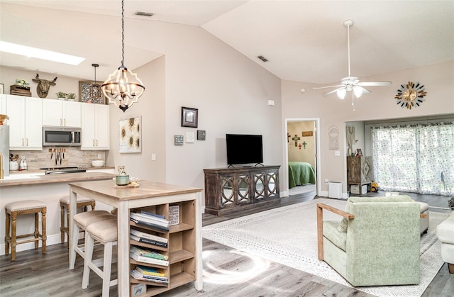 2403 Nantucket Field Way Unit 27, Sun City Center, FL 33573 - living area featuring light wood finished floors, a chandelier, ceiling fan, high vaulted ceiling, and baseboards