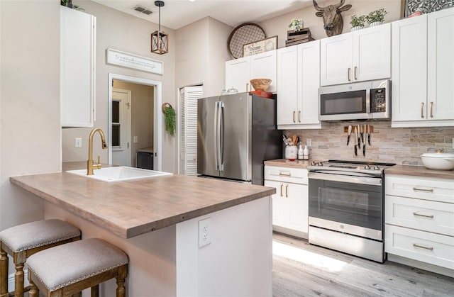 2403 Nantucket Field Way Unit 27, Sun City Center, FL 33573 - kitchen featuring appliances with stainless steel finishes, wooden counters, decorative backsplash, a sink, and a kitchen breakfast bar