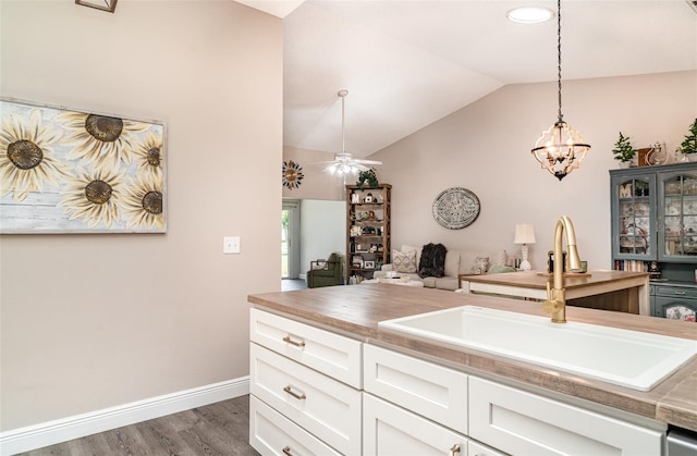 2403 Nantucket Field Way Unit 27, Sun City Center, FL 33573 - kitchen featuring a sink, vaulted ceiling, dark wood finished floors, open floor plan, and white cabinets