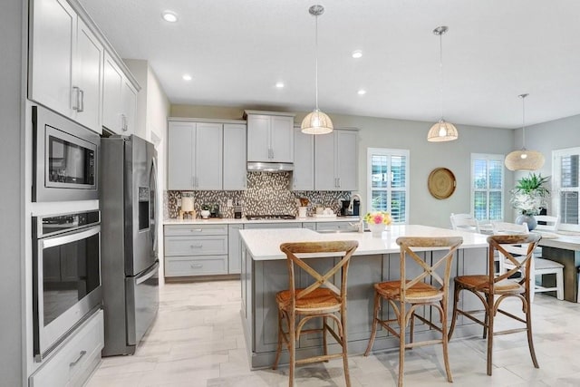 6097 Golden Nettle Dr, Apollo Beach, FL 33572 - kitchen featuring stainless steel appliances, a sink, under cabinet range hood, backsplash, and light countertops