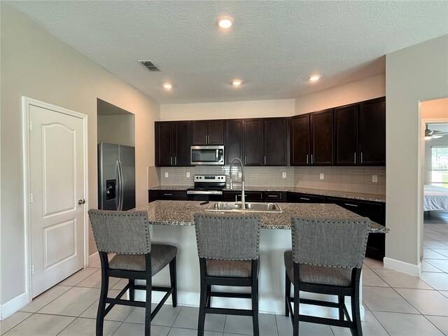1509 Venice Ln, Davenport, FL 33896 - kitchen featuring appliances with stainless steel finishes, a sink, backsplash, a breakfast bar, and a textured ceiling