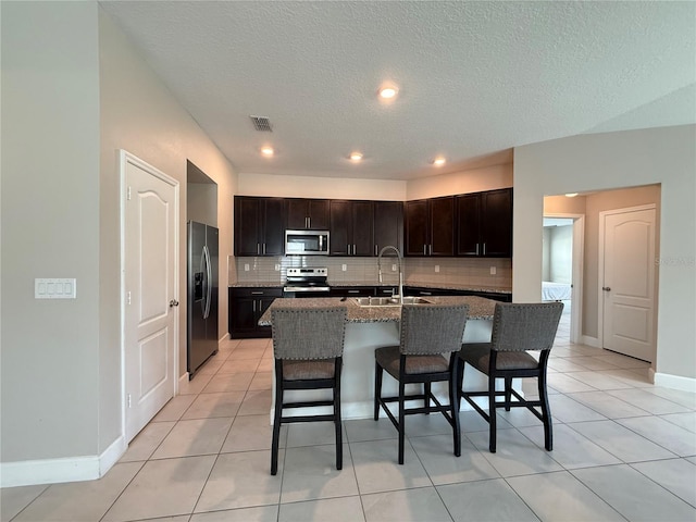 1509 Venice Ln, Davenport, FL 33896 - kitchen with stainless steel appliances, tasteful backsplash, a sink, a breakfast bar area, and a textured ceiling