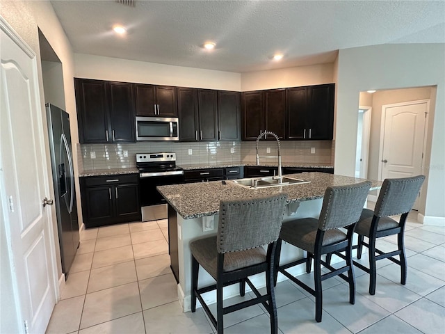 1509 Venice Ln, Davenport, FL 33896 - kitchen with stainless steel appliances, a sink, decorative backsplash, a breakfast bar, and a textured ceiling