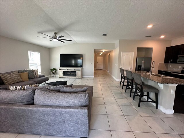 1509 Venice Ln, Davenport, FL 33896 - living area featuring light tile patterned floors, a ceiling fan, vaulted ceiling, baseboards, and a textured ceiling