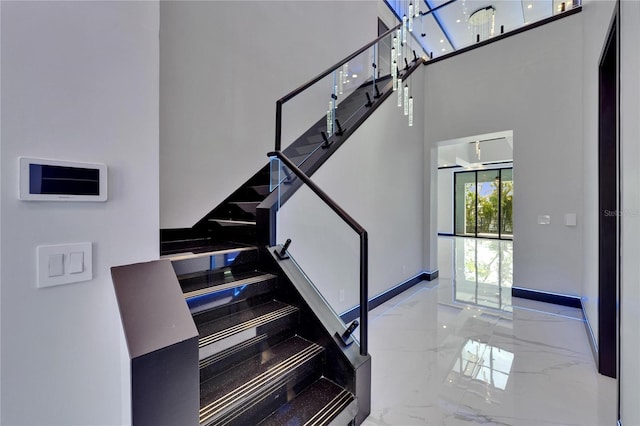 6530 Simone Shores Cir, Apollo Beach, FL 33572 - staircase featuring marble tiled floors, a towering ceiling, and baseboards